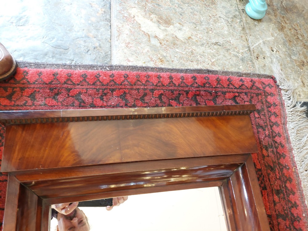 A tall early nineteenth-century Biedermeier mahogany pier mirror featuring a stepped top cornice, a carved floral frieze panel, and a rectangular glass plate. View IV