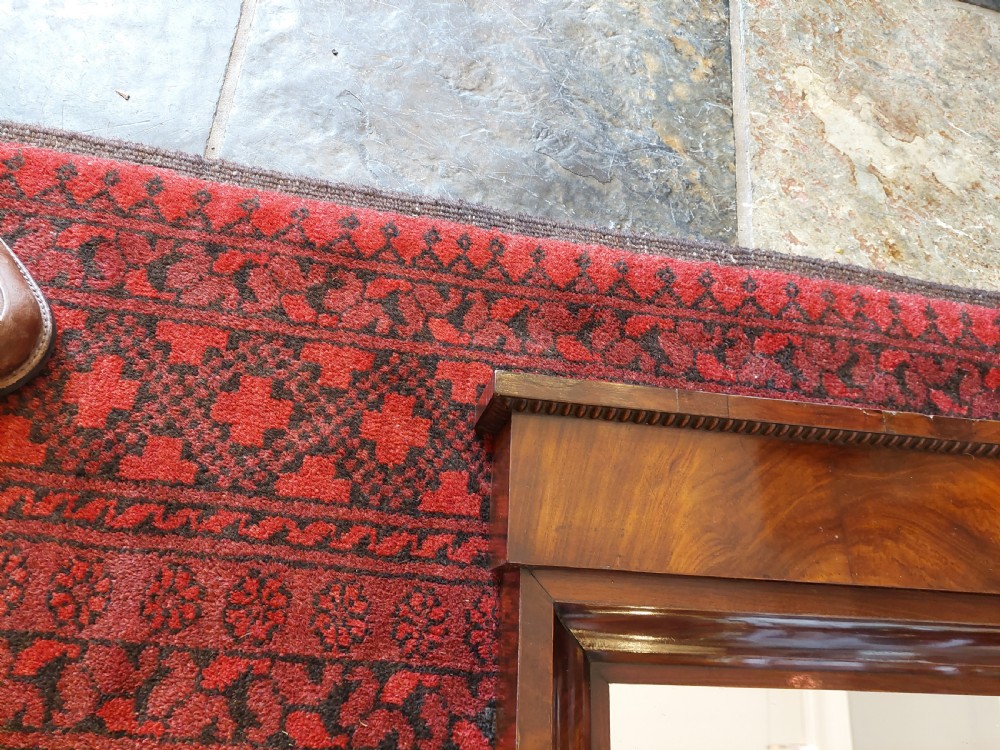 A tall early nineteenth-century Biedermeier mahogany pier mirror featuring a stepped top cornice, a carved floral frieze panel, and a rectangular glass plate. View VI