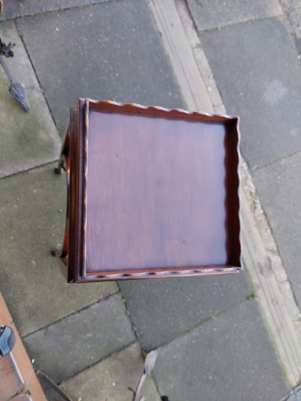 An Edwardian Art Nouveau dark mahogany jardiniere stand featuring a scalloped rim top, pierced apron detailing, arched legs, and a lower square undertier. View II