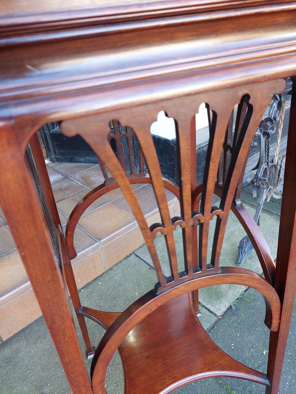 An Edwardian Art Nouveau dark mahogany jardiniere stand featuring a scalloped rim top, pierced apron detailing, arched legs, and a lower square undertier. View III