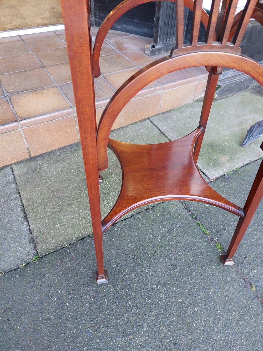 An Edwardian Art Nouveau dark mahogany jardiniere stand featuring a scalloped rim top, pierced apron detailing, arched legs, and a lower square undertier. View V