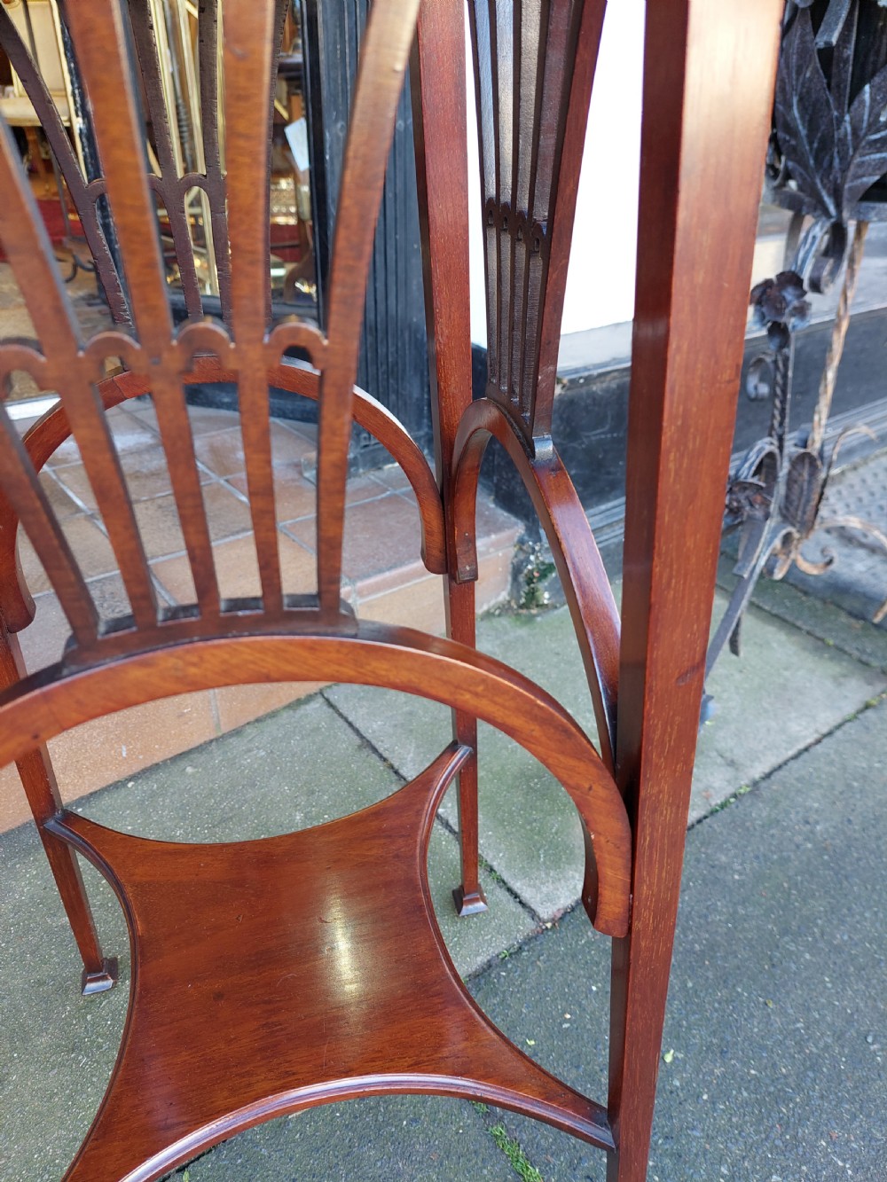 An Edwardian Art Nouveau dark mahogany jardiniere stand featuring a scalloped rim top, pierced apron detailing, arched legs, and a lower square undertier. View VI