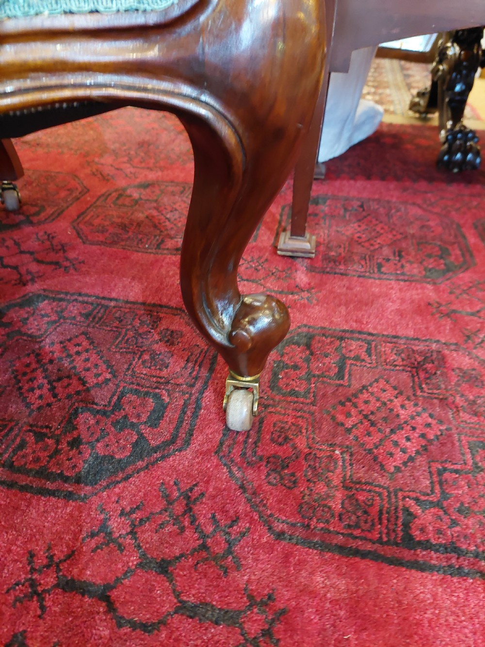 Victorian mahogany scroll frame armchair upholstered in a dark botanical floral fabric with a button-backed cushion and carved cabriole legs on castors. View III