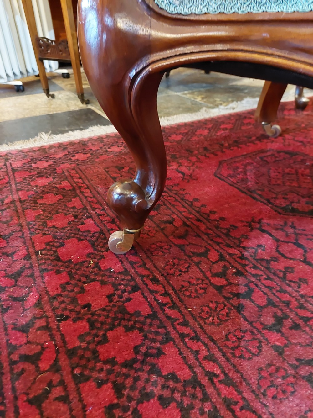 Victorian mahogany scroll frame armchair upholstered in a dark botanical floral fabric with a button-backed cushion and carved cabriole legs on castors. View IV