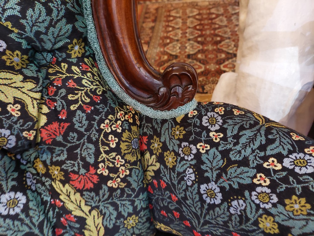 Victorian mahogany scroll frame armchair upholstered in a dark botanical floral fabric with a button-backed cushion and carved cabriole legs on castors. View VI