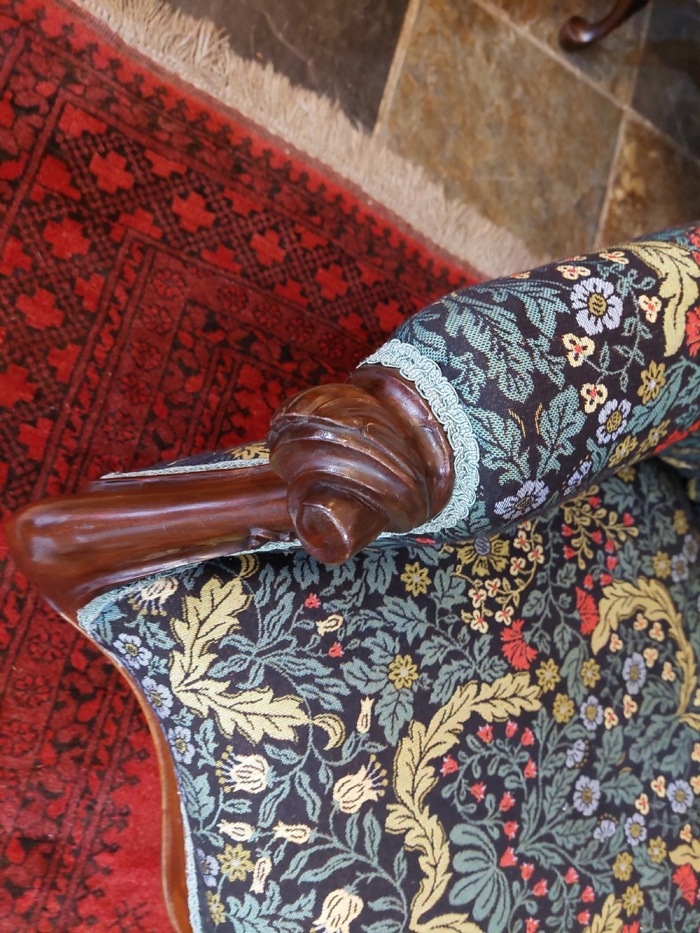 Victorian mahogany scroll frame armchair upholstered in a dark botanical floral fabric with a button-backed cushion and carved cabriole legs on castors. View VII