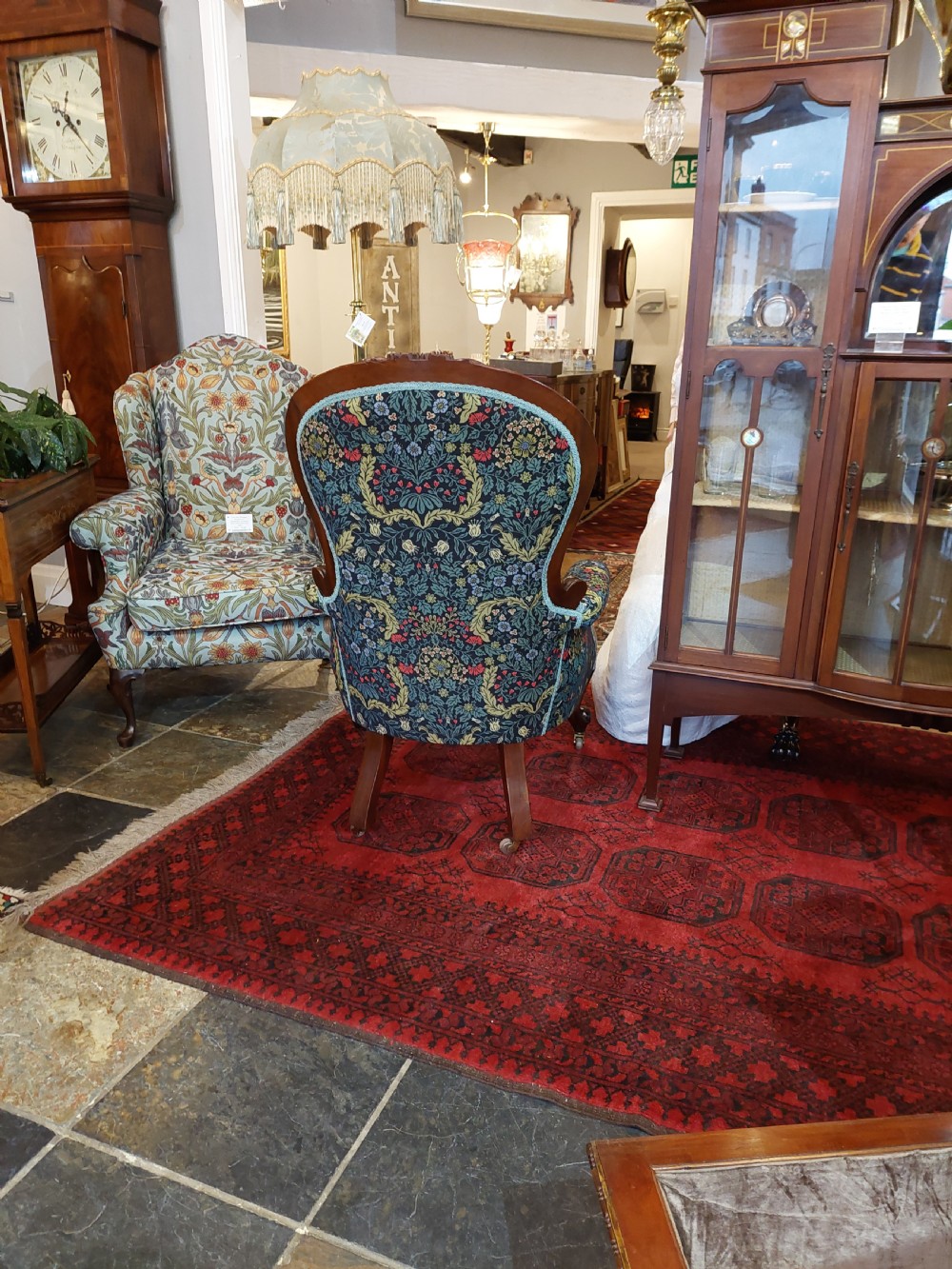Victorian mahogany scroll frame armchair upholstered in a dark botanical floral fabric with a button-backed cushion and carved cabriole legs on castors. View IX