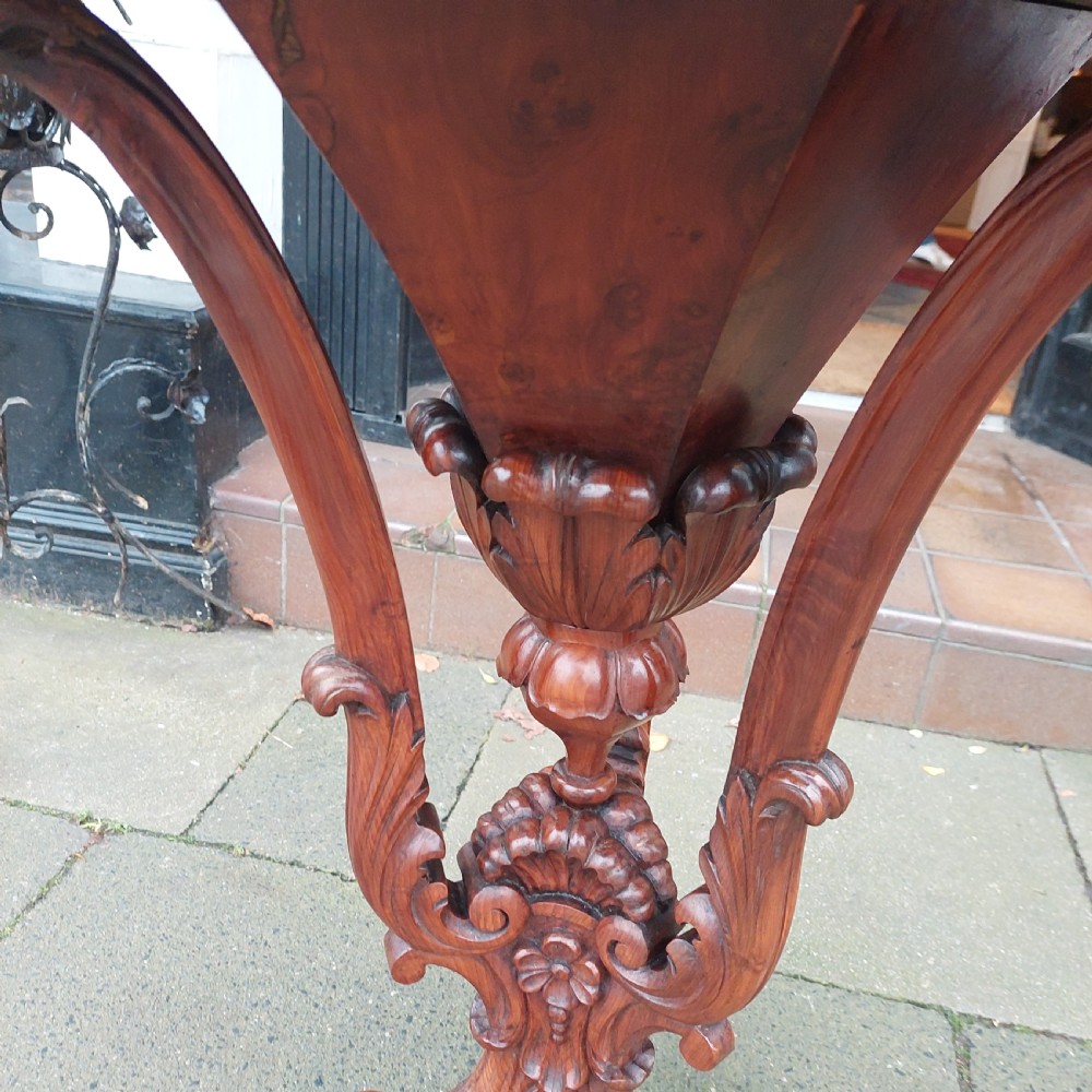 A 19th-century octagonal yew wood work table featuring a hinged top lid, a tapered central body, and carved tripod legs. View VI