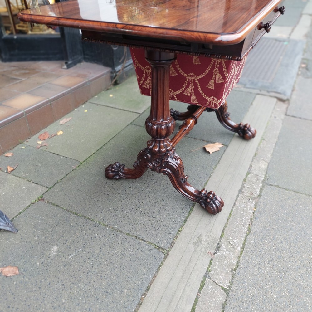 A Regency rosewood work table featuring drop leaves, a single frieze drawer, a red patterned fabric sewing well below, turned pedestal supports, and carved claw feet. View III