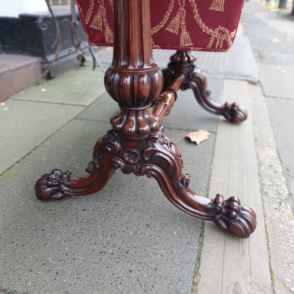 A Regency rosewood work table featuring drop leaves, a single frieze drawer, a red patterned fabric sewing well below, turned pedestal supports, and carved claw feet. View V