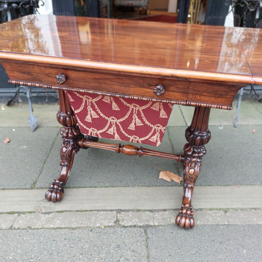 A Regency rosewood work table featuring drop leaves, a single frieze drawer, a red patterned fabric sewing well below, turned pedestal supports, and carved claw feet. View VII