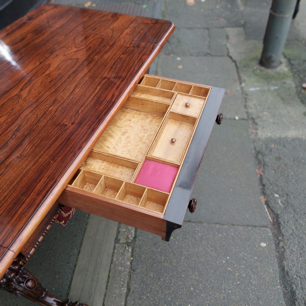 A Regency rosewood work table featuring drop leaves, a single frieze drawer, a red patterned fabric sewing well below, turned pedestal supports, and carved claw feet. View VIII