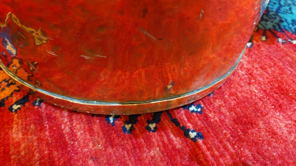 A circular Victorian copper log bucket featuring visible rivet construction along the seams and a brass swing handle. View VI