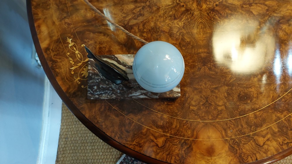 An Art Deco table lamp featuring a black sculptural fish figure beside a spherical glass shade on a rectangular marbled base. View IV