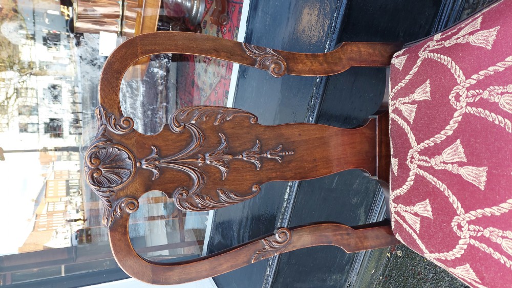 A pair of late 19th-century Queen Anne style carved mahogany side chairs with shell motif crests, splat backs, cabriole legs with claw and ball feet, and red patterned fabric seats. View V