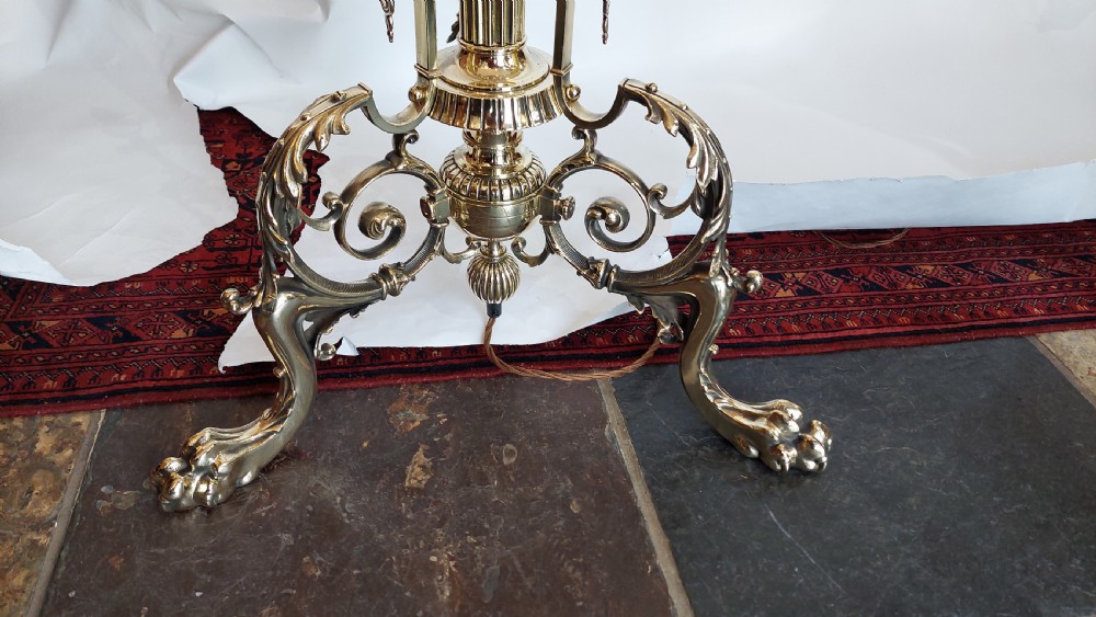 An ornate Victorian brass adjustable standard lamp featuring a scrolled tripod base with paw feet and a fabric shade with fringed tassels. View VII