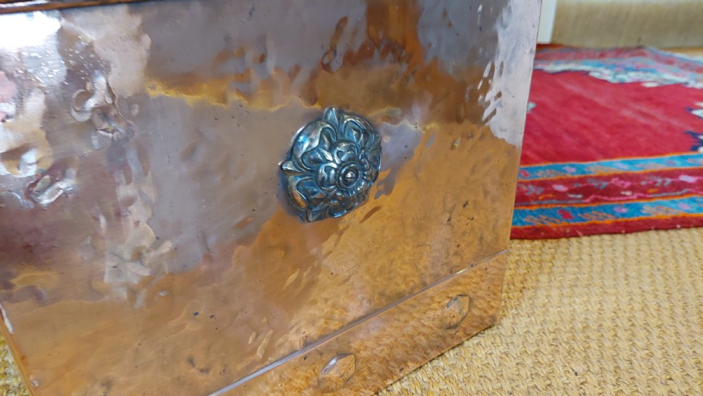 A late 19th-century square copper-plated coal box featuring a hammered finish, hinged lid, drop side handles, and decorative metal studs along the base. View III