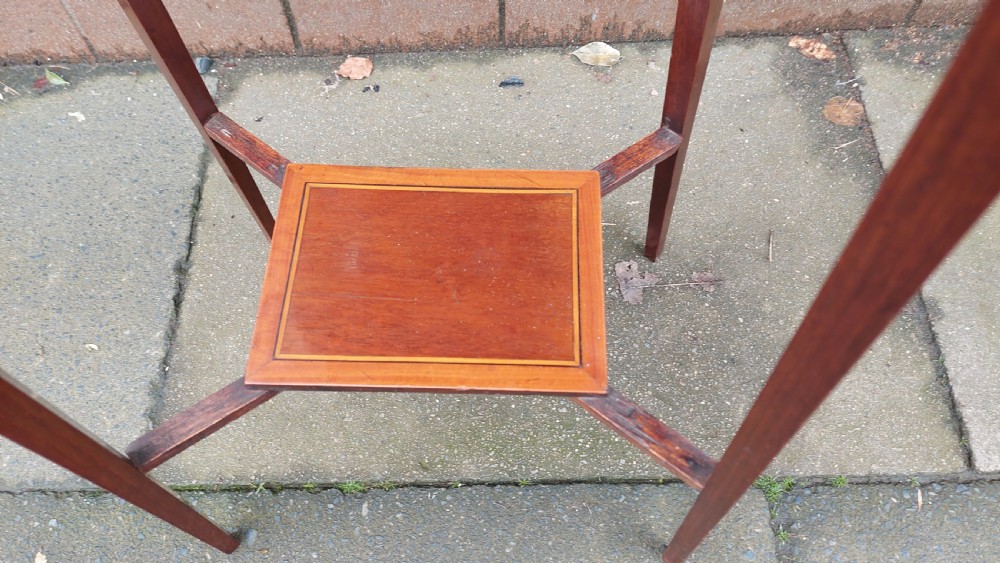 An Edwardian mahogany torchere stand featuring an octagonal top with satinwood inlay, four slender splayed legs, and a square lower undertier. View IV