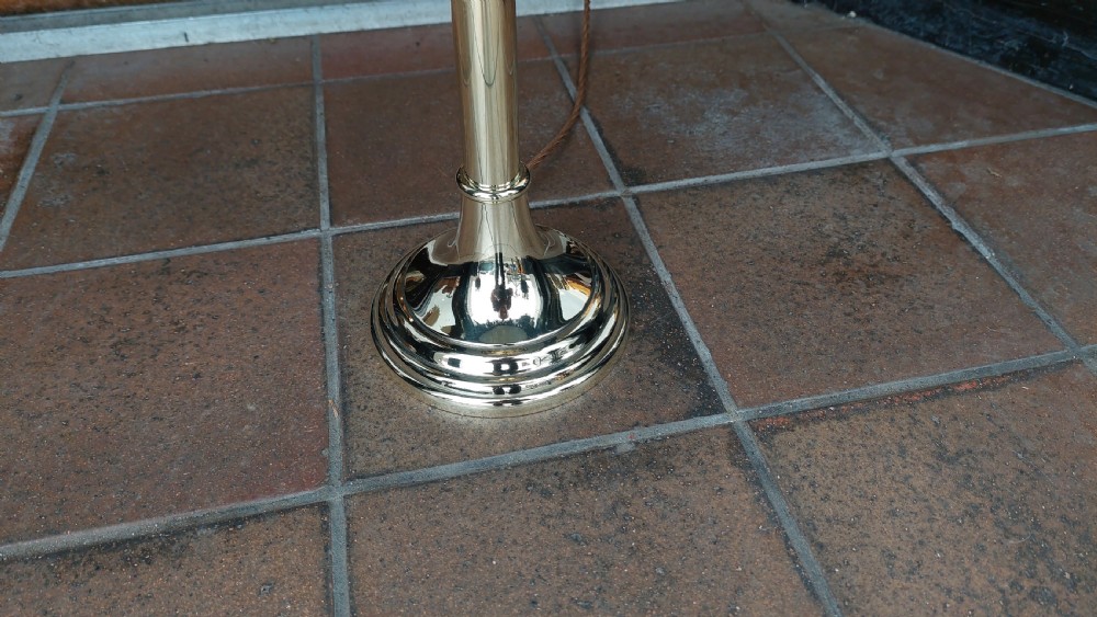 A pair of turned brass candlestands fitted with deep blue fringed dome shades decorated with a floral motif. View II