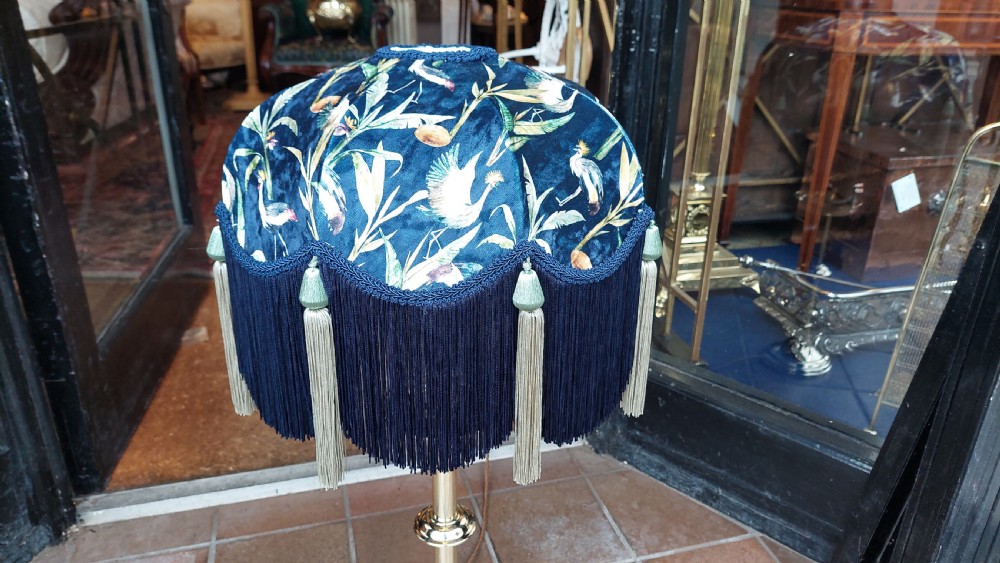 A pair of turned brass candlestands fitted with deep blue fringed dome shades decorated with a floral motif. View IV