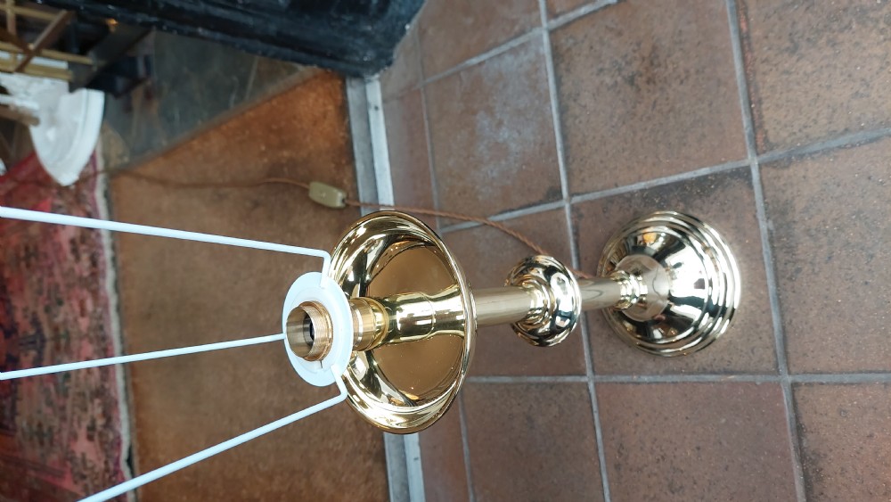 A pair of turned brass candlestands fitted with deep blue fringed dome shades decorated with a floral motif. View V