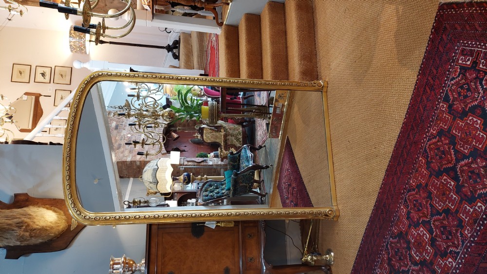 A large Victorian giltwood mirror featuring an arched upper frame, detailed bead moulding, and carved scroll feet at the base. View II