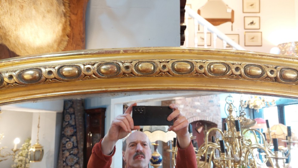 A large Victorian giltwood mirror featuring an arched upper frame, detailed bead moulding, and carved scroll feet at the base. View IV