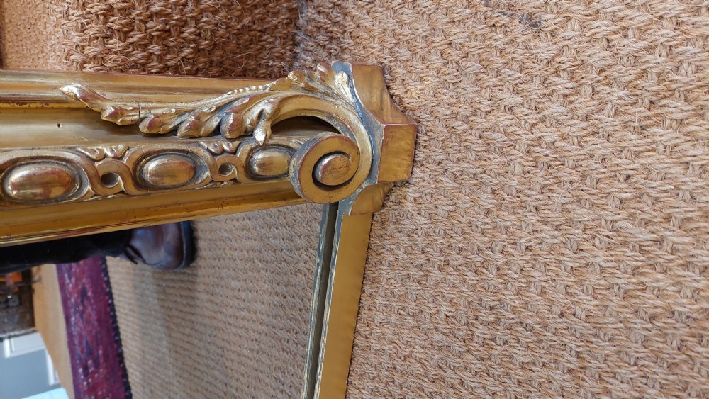 A large Victorian giltwood mirror featuring an arched upper frame, detailed bead moulding, and carved scroll feet at the base. View VI