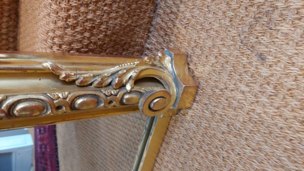 A large Victorian giltwood mirror featuring an arched upper frame, detailed bead moulding, and carved scroll feet at the base. View VII