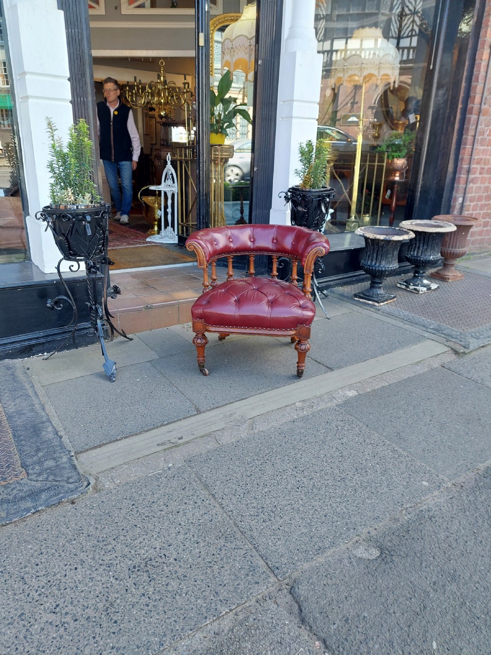 A Victorian mahogany captains desk chair featuring deep-buttoned burgundy leather upholstery, brass stud trim, turned spindles, and carved legs on brass castors. View II