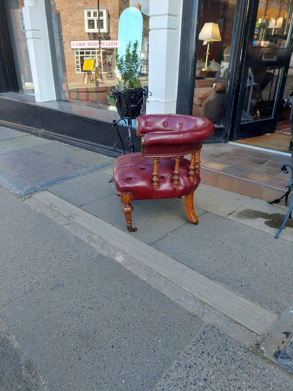 A Victorian mahogany captains desk chair featuring deep-buttoned burgundy leather upholstery, brass stud trim, turned spindles, and carved legs on brass castors. View III