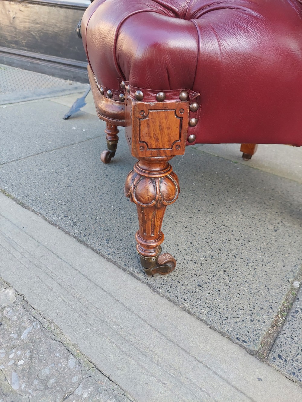A Victorian mahogany captains desk chair featuring deep-buttoned burgundy leather upholstery, brass stud trim, turned spindles, and carved legs on brass castors. View IV
