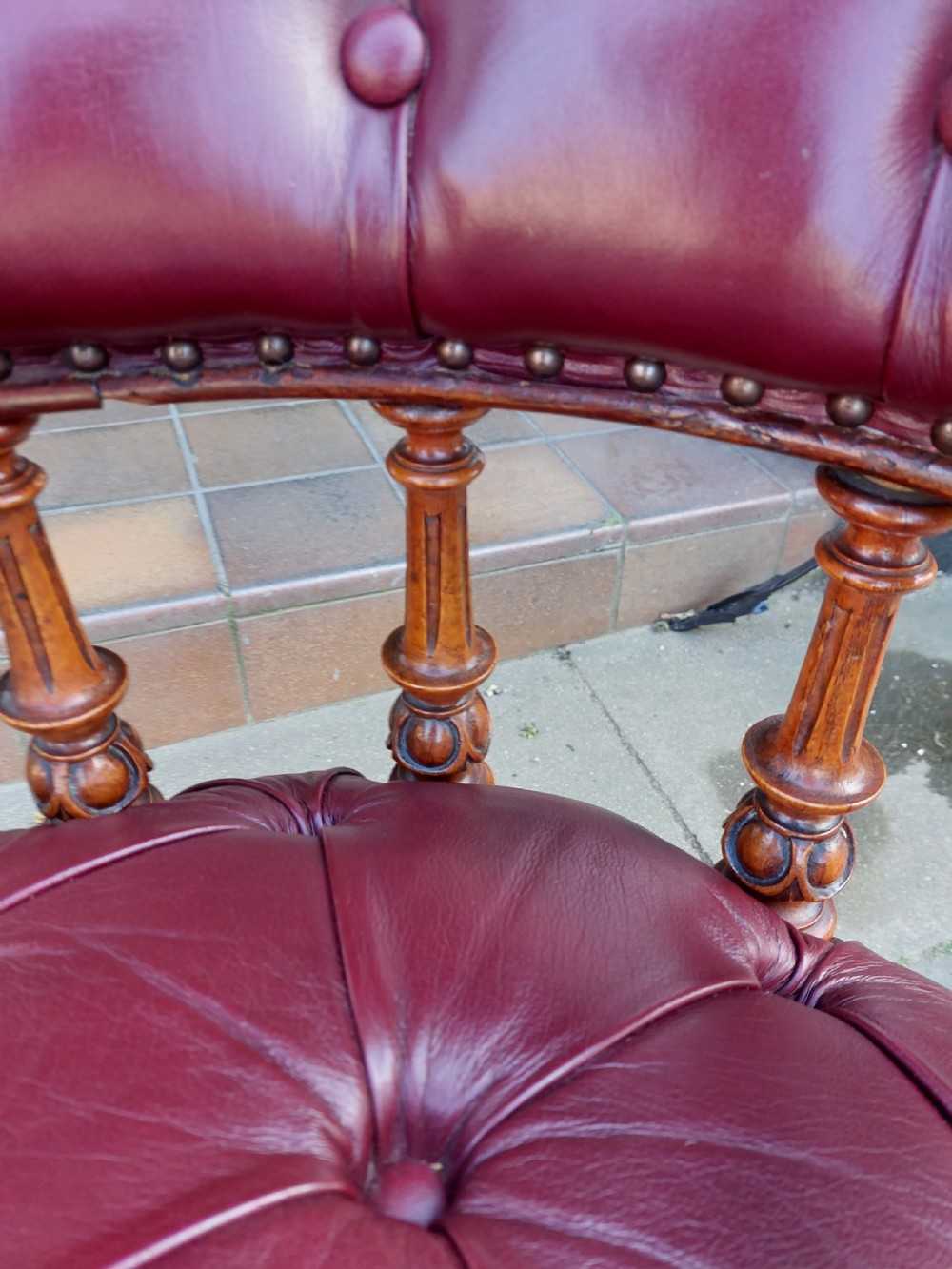 A Victorian mahogany captains desk chair featuring deep-buttoned burgundy leather upholstery, brass stud trim, turned spindles, and carved legs on brass castors. View VIII
