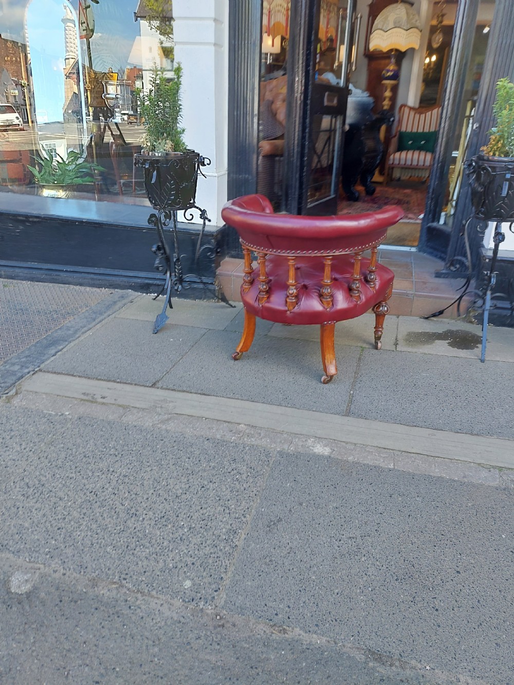 A Victorian mahogany captains desk chair featuring deep-buttoned burgundy leather upholstery, brass stud trim, turned spindles, and carved legs on brass castors. View IX