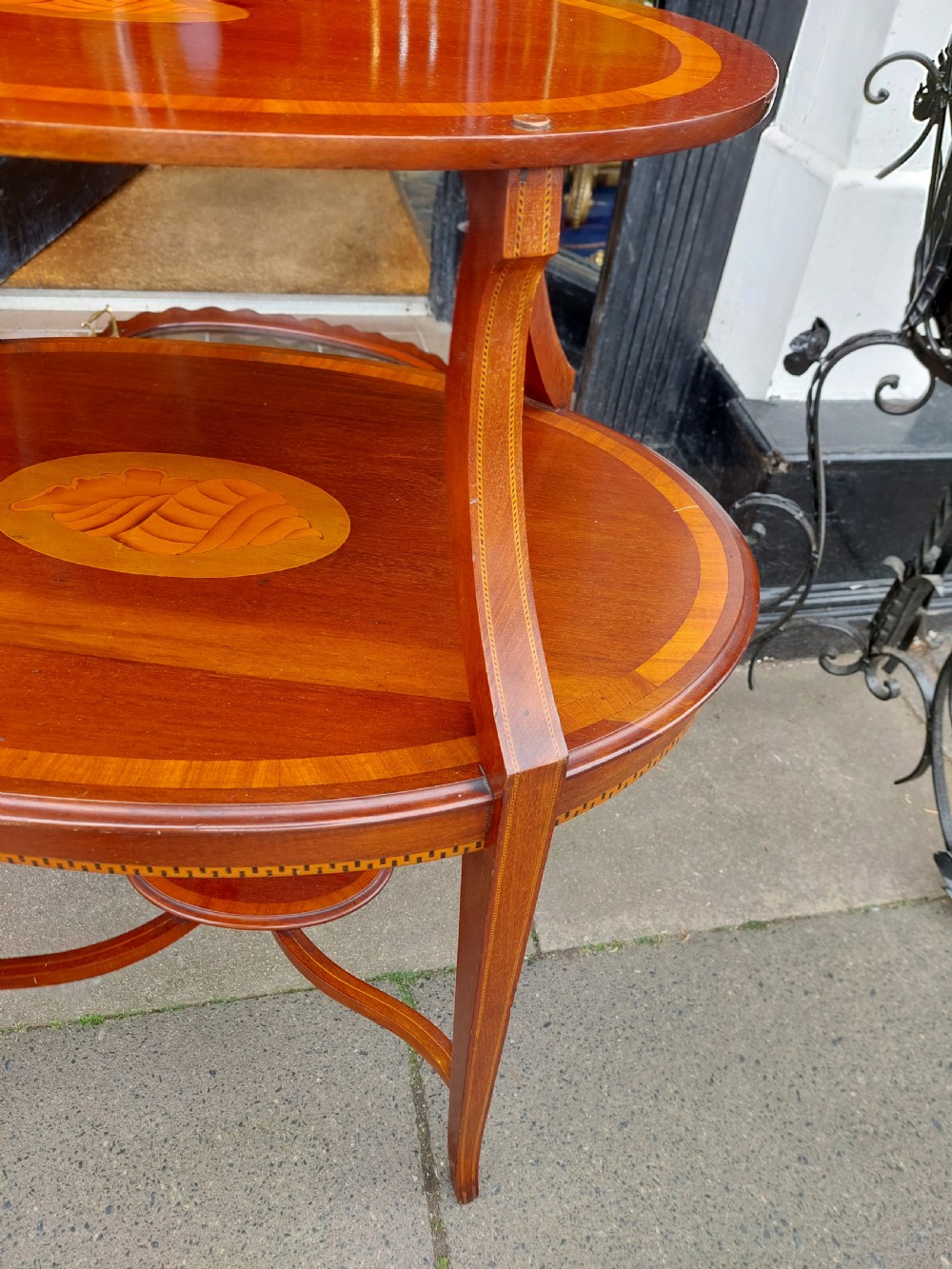 An Edwardian mahogany two-tier etagere table with satinwood oval inlays, brass side handles, and a removable glass tray top. View V
