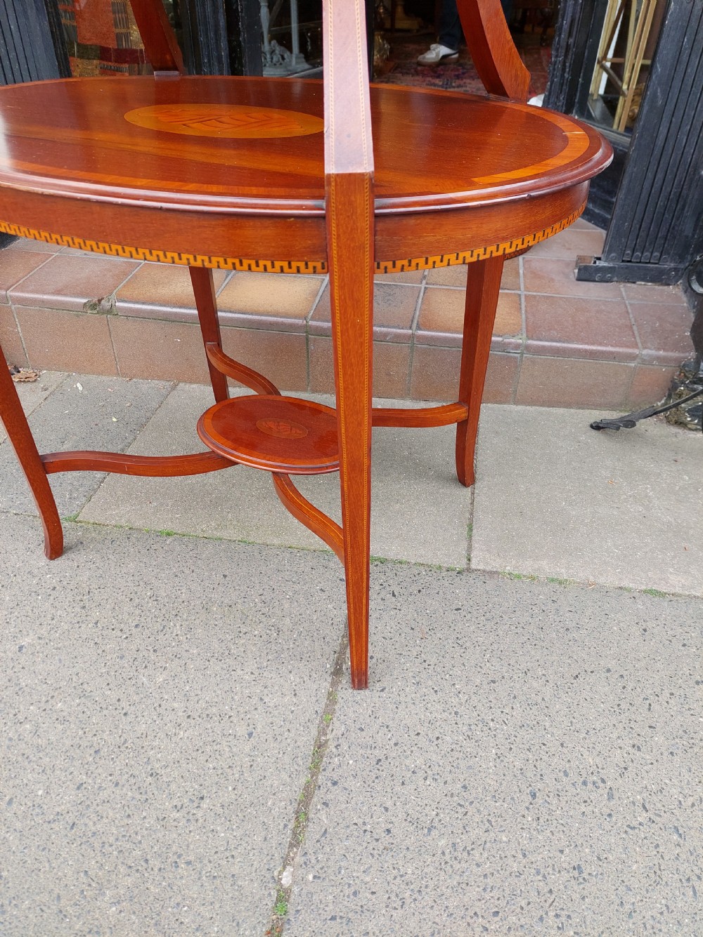 An Edwardian mahogany two-tier etagere table with satinwood oval inlays, brass side handles, and a removable glass tray top. View IX
