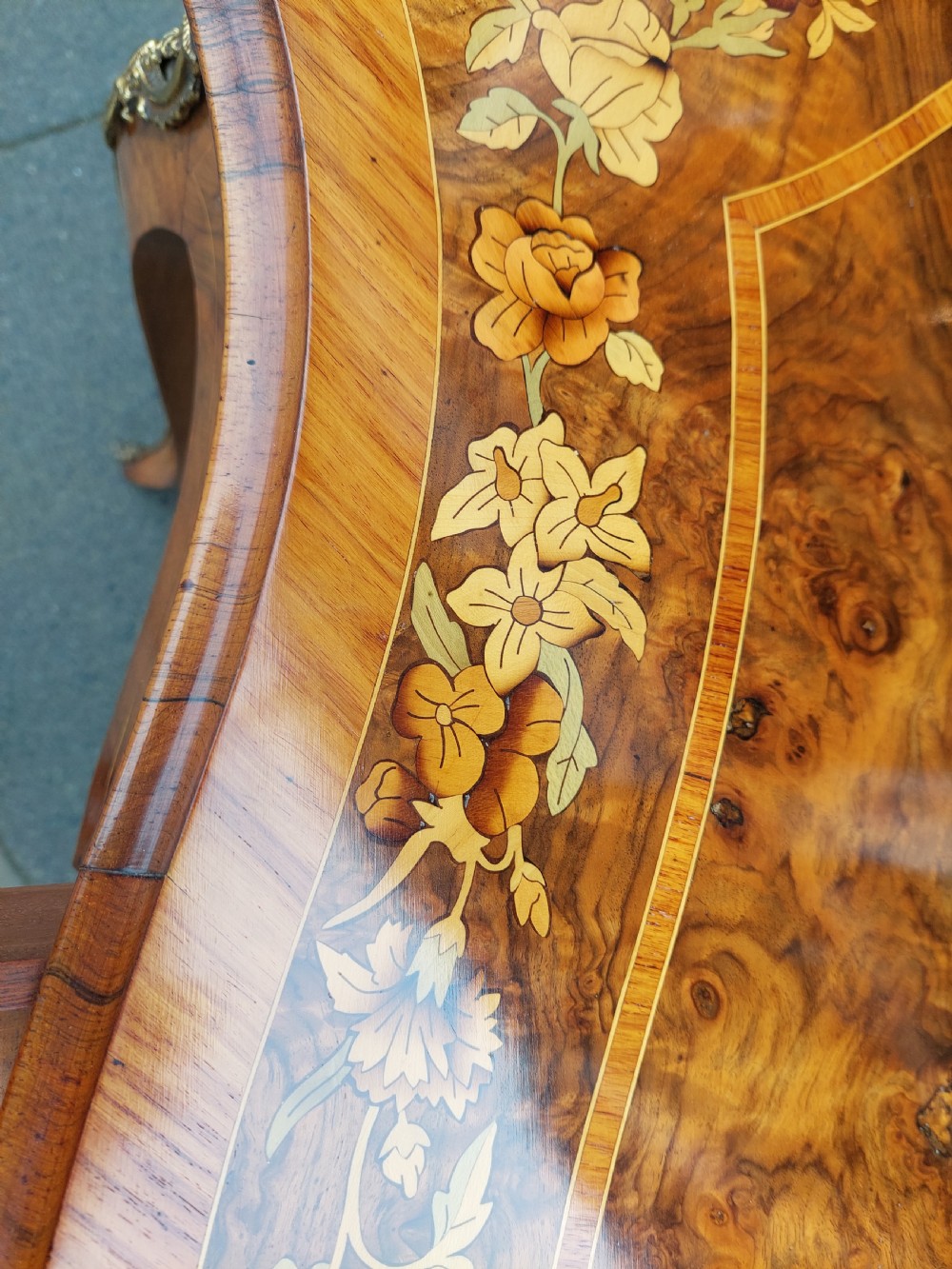 A 19th-century burr walnut bureau plat with a serpentine top featuring floral marquetry, gilt-bronze mounts, and cabriole legs. View VI