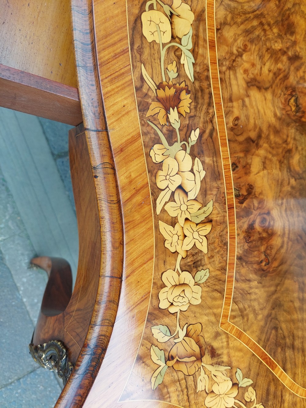 A 19th-century burr walnut bureau plat with a serpentine top featuring floral marquetry, gilt-bronze mounts, and cabriole legs. View VII