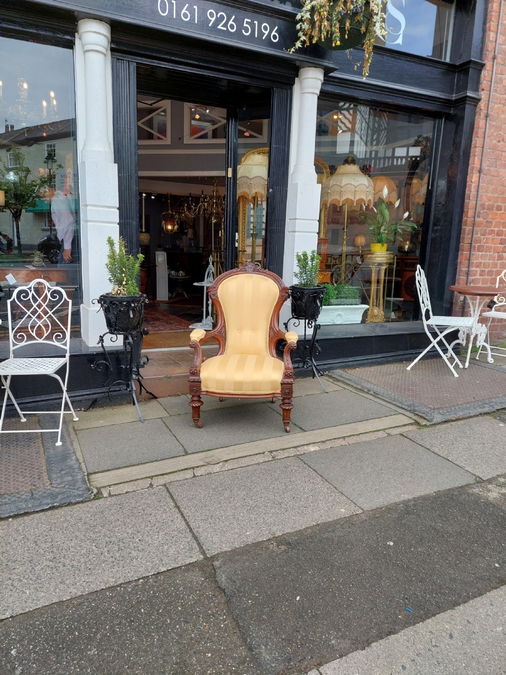 A low Victorian armchair crafted from carved dark walnut with cream striped upholstery and turned legs with brass casters. View II