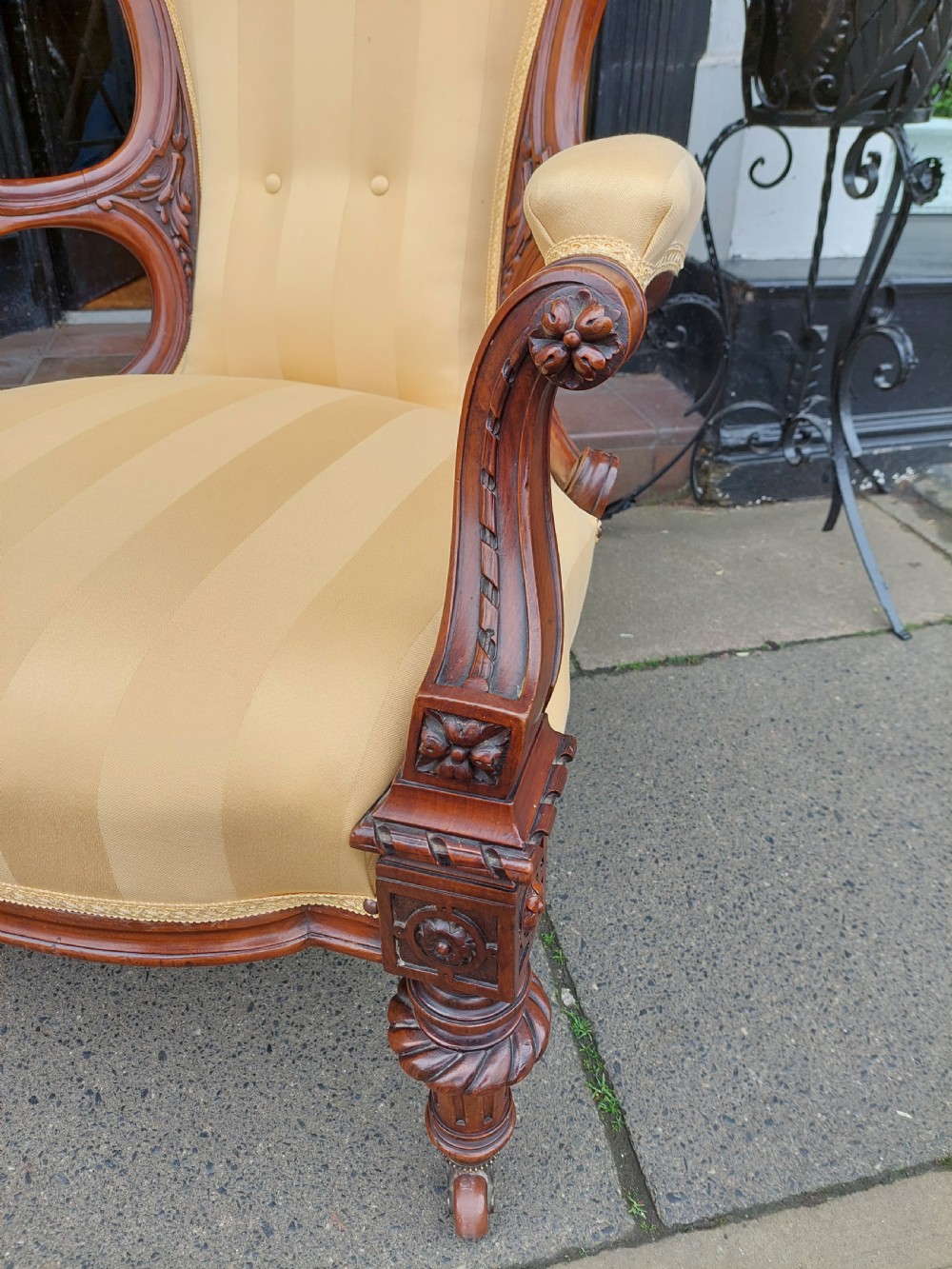 A low Victorian armchair crafted from carved dark walnut with cream striped upholstery and turned legs with brass casters. View III