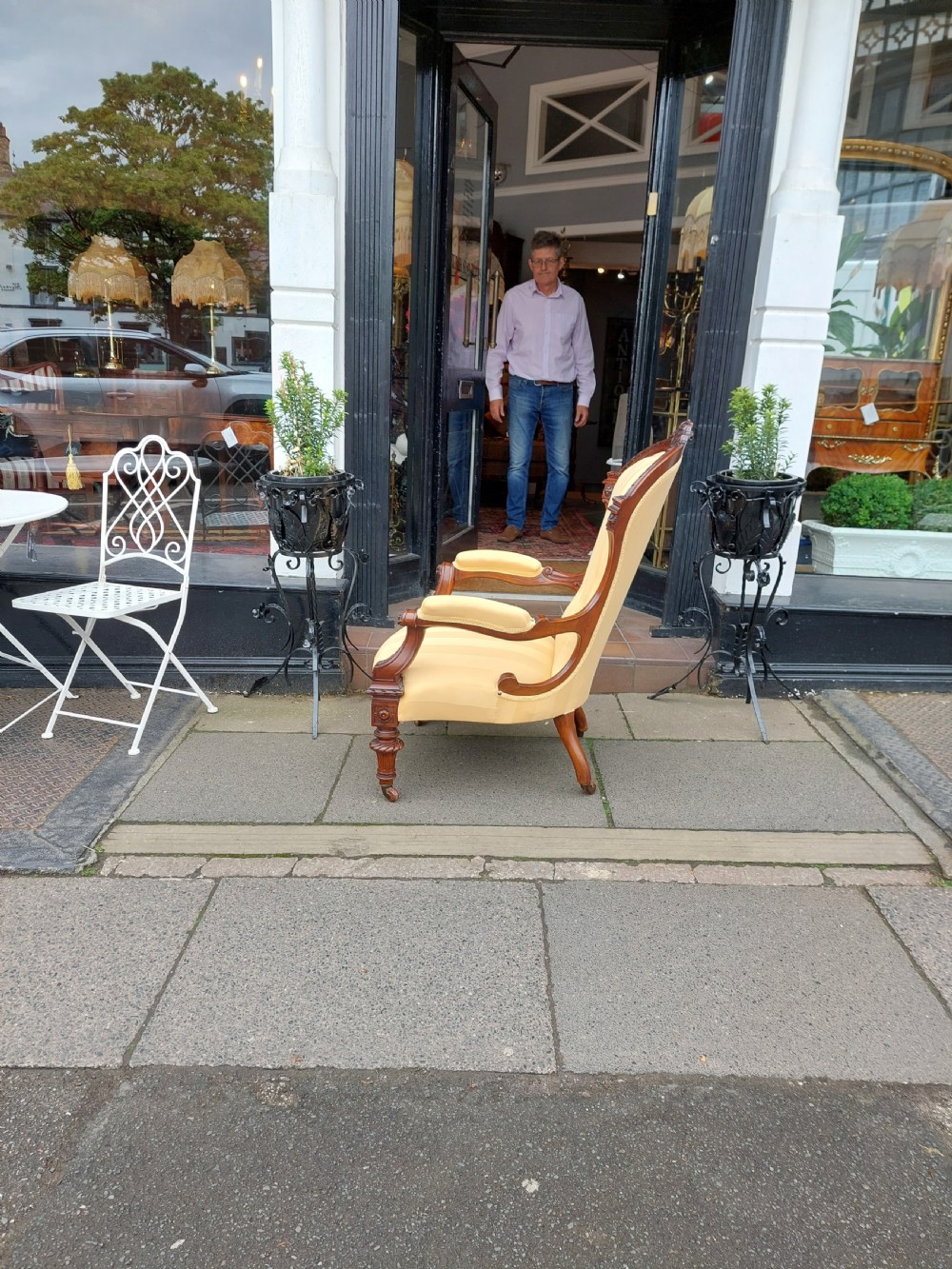 A low Victorian armchair crafted from carved dark walnut with cream striped upholstery and turned legs with brass casters. View IX