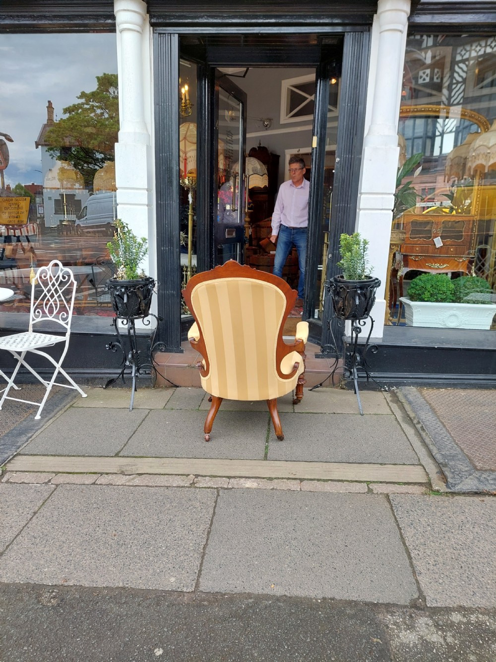 A low Victorian armchair crafted from carved dark walnut with cream striped upholstery and turned legs with brass casters. View X