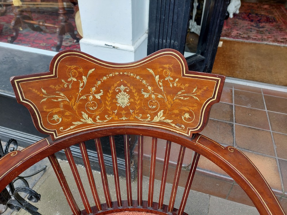 A matched pair of Edwardian mahogany tub armchairs featuring floral marquetry backsplats, thin vertical spindles, cabriole legs, and red patterned fabric seats. View II