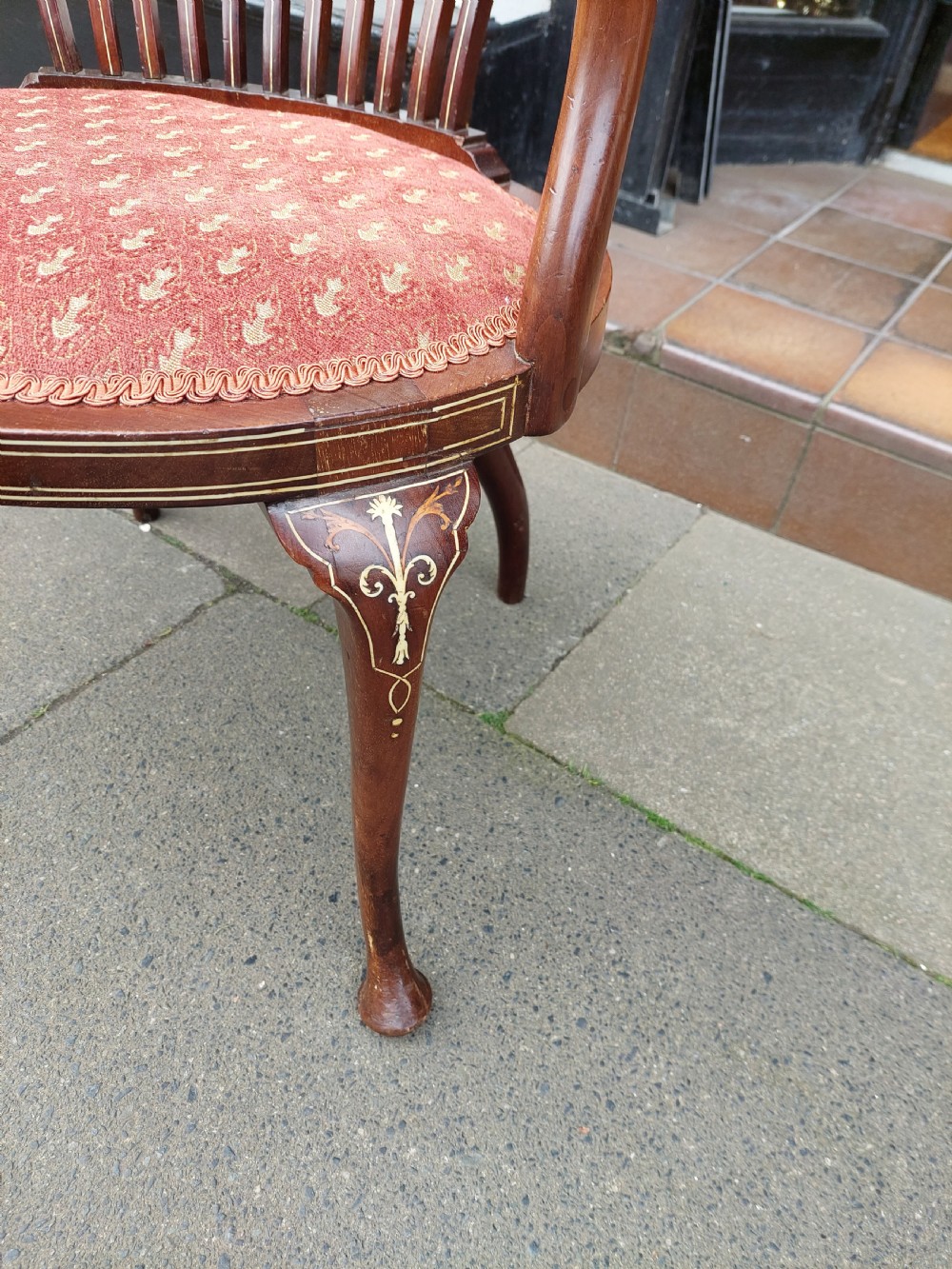 A matched pair of Edwardian mahogany tub armchairs featuring floral marquetry backsplats, thin vertical spindles, cabriole legs, and red patterned fabric seats. View IV
