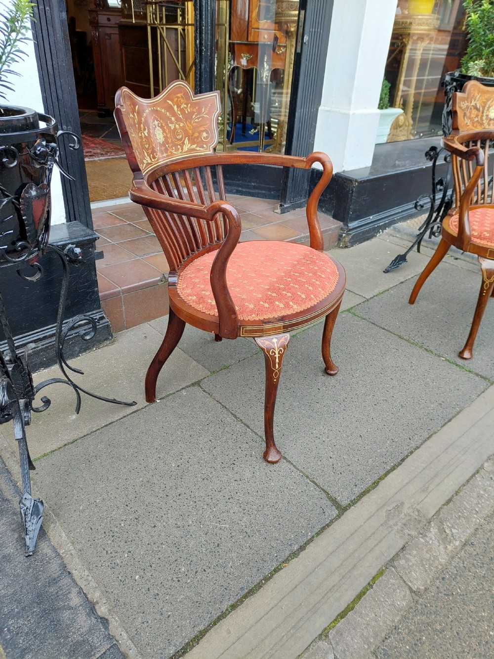 A matched pair of Edwardian mahogany tub armchairs featuring floral marquetry backsplats, thin vertical spindles, cabriole legs, and red patterned fabric seats. View VI