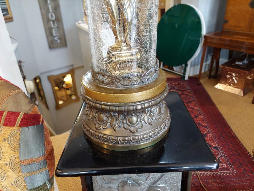 A pair of ornate gilded spelter table lamps featuring classical figures enclosed in glass columns topped with fringed cream fabric shades. View V