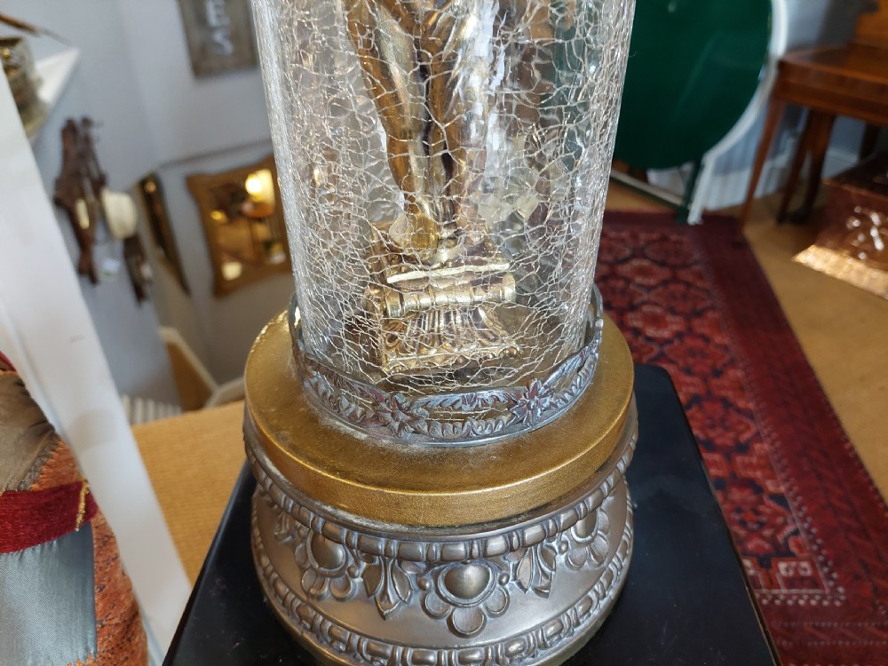 A pair of ornate gilded spelter table lamps featuring classical figures enclosed in glass columns topped with fringed cream fabric shades. View VII