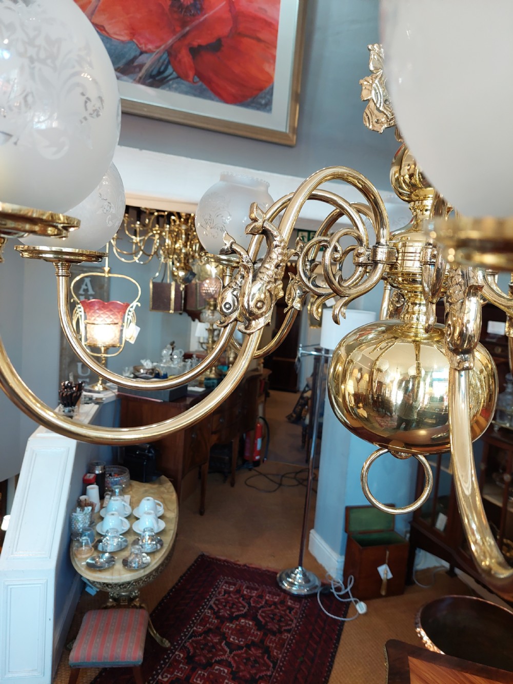An early twentieth-century polished brass eight-arm chandelier featuring etched frosted glass shades mounted on curved arms around a central baluster stem. View II