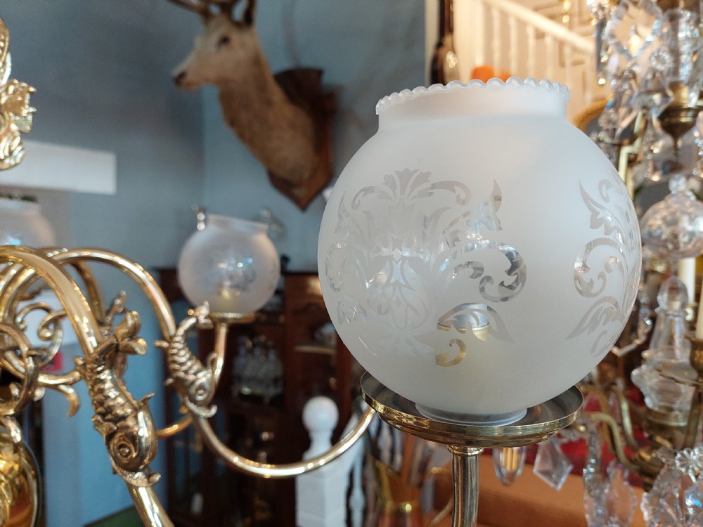 An early twentieth-century polished brass eight-arm chandelier featuring etched frosted glass shades mounted on curved arms around a central baluster stem. View IV