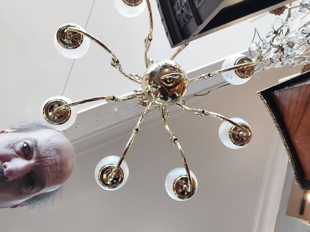 An early twentieth-century polished brass eight-arm chandelier featuring etched frosted glass shades mounted on curved arms around a central baluster stem. View VI